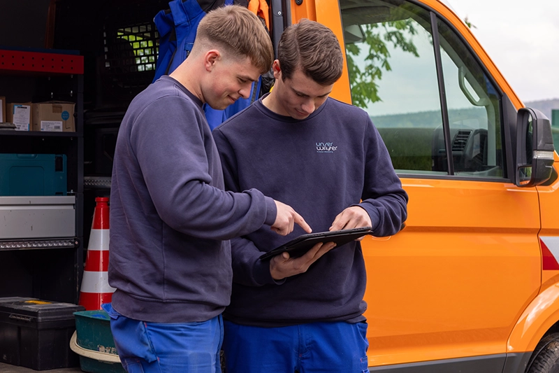 Zwei Mitarbeiter schauen überprüfend auf ihr Service-Tablet.